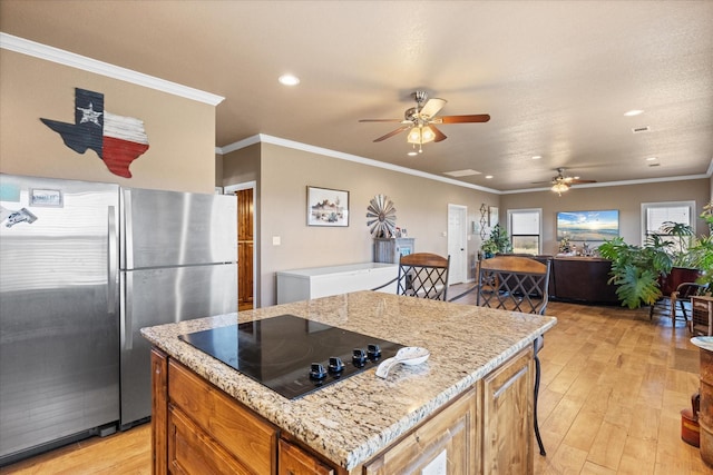 kitchen featuring black electric cooktop, stainless steel refrigerator, ornamental molding, and light stone counters