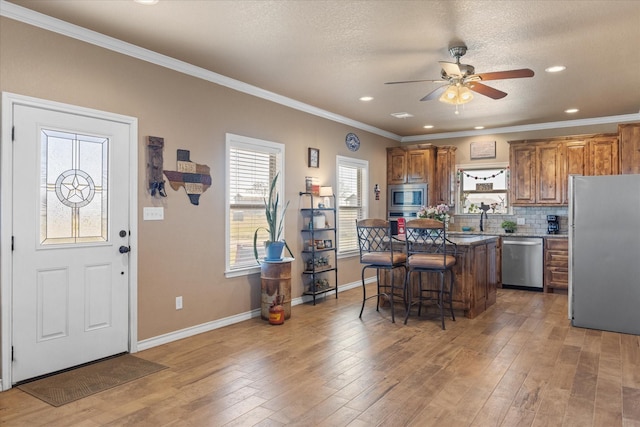 kitchen with hardwood / wood-style flooring, a kitchen breakfast bar, a center island, and appliances with stainless steel finishes