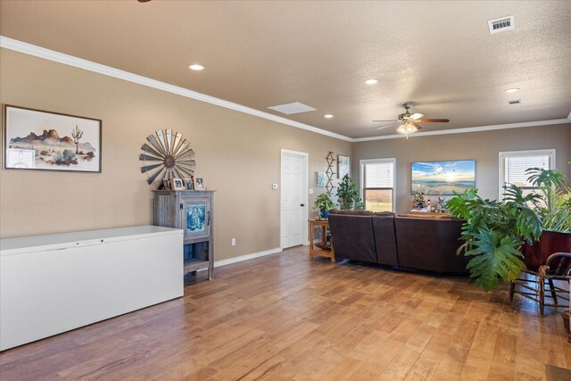 living room featuring ceiling fan, wood-type flooring, a textured ceiling, and ornamental molding