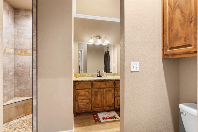 bathroom with vanity, crown molding, hardwood / wood-style flooring, toilet, and walk in shower