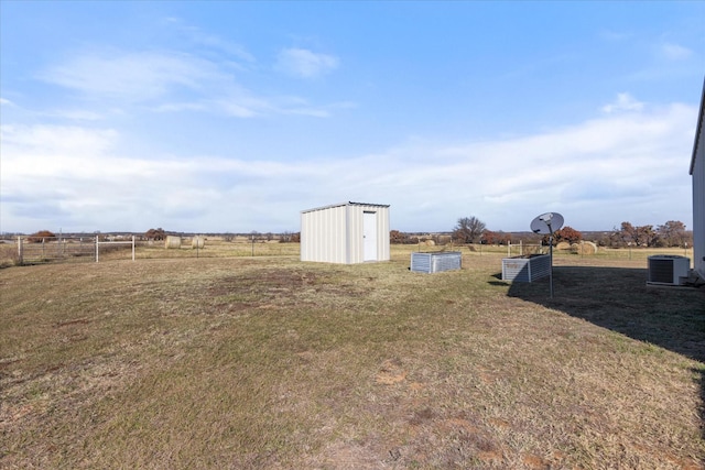 view of yard featuring a rural view, central AC unit, and a storage shed