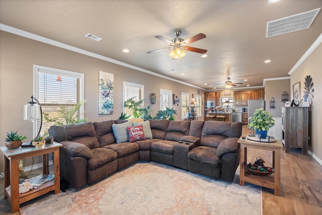 living room with ceiling fan, light wood-type flooring, and ornamental molding