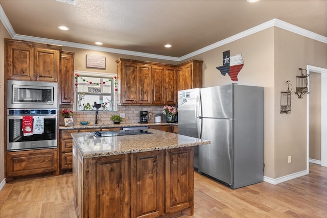 kitchen with light stone countertops, stainless steel appliances, a kitchen island, and light hardwood / wood-style floors