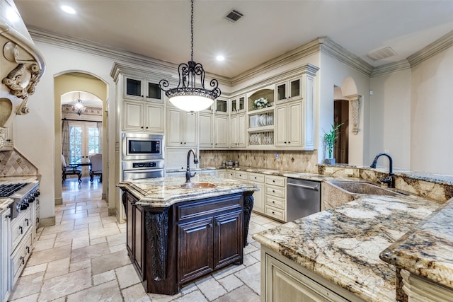 kitchen featuring sink, light stone counters, a center island with sink, appliances with stainless steel finishes, and pendant lighting