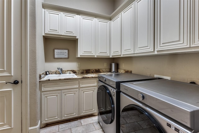 clothes washing area featuring cabinets, sink, and washing machine and clothes dryer