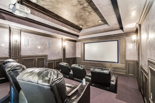 carpeted home theater featuring ornamental molding and a raised ceiling