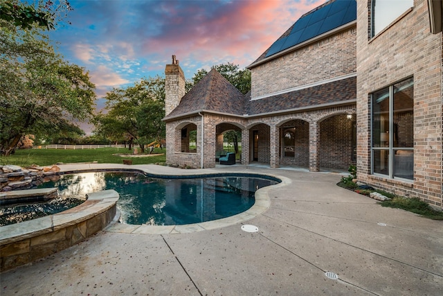 pool at dusk featuring a patio