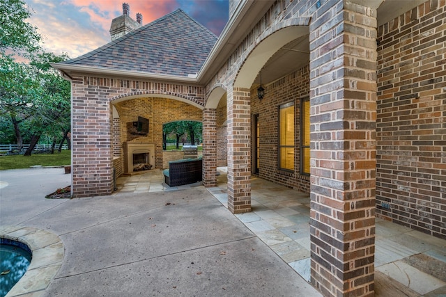 patio terrace at dusk featuring exterior fireplace