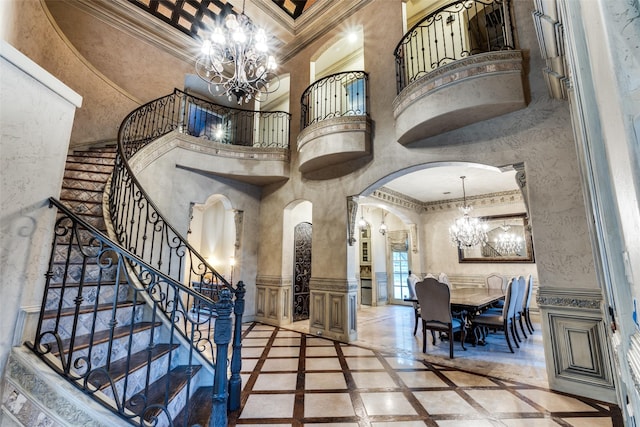 entrance foyer with a high ceiling, crown molding, and a chandelier