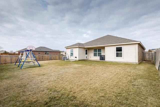 rear view of property with a playground, a yard, and cooling unit