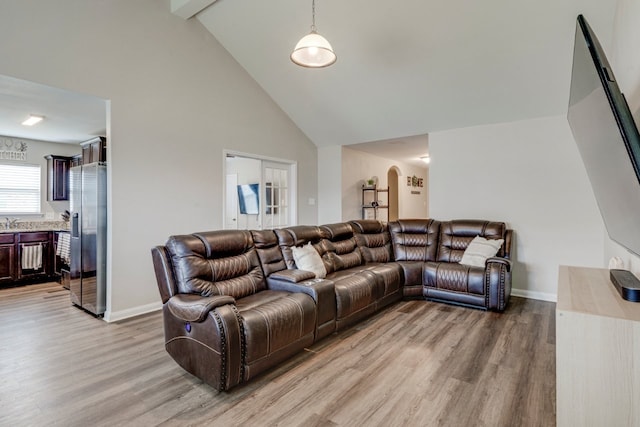 living room with wood-type flooring, high vaulted ceiling, and beamed ceiling