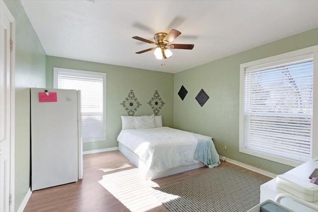 bedroom featuring light wood-type flooring, white fridge, and ceiling fan