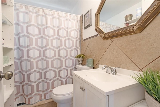 bathroom with vanity, tile walls, and toilet