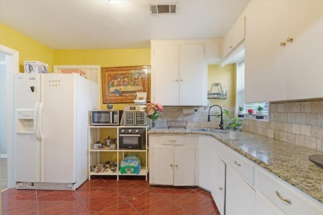 kitchen with white cabinets, backsplash, white fridge with ice dispenser, and sink