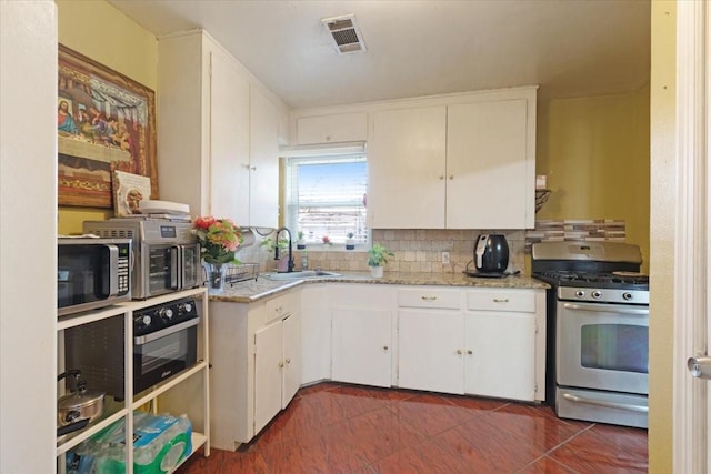 kitchen with decorative backsplash, appliances with stainless steel finishes, sink, dark tile patterned flooring, and white cabinets