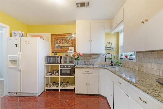 kitchen featuring white cabinets, backsplash, white fridge with ice dispenser, and sink