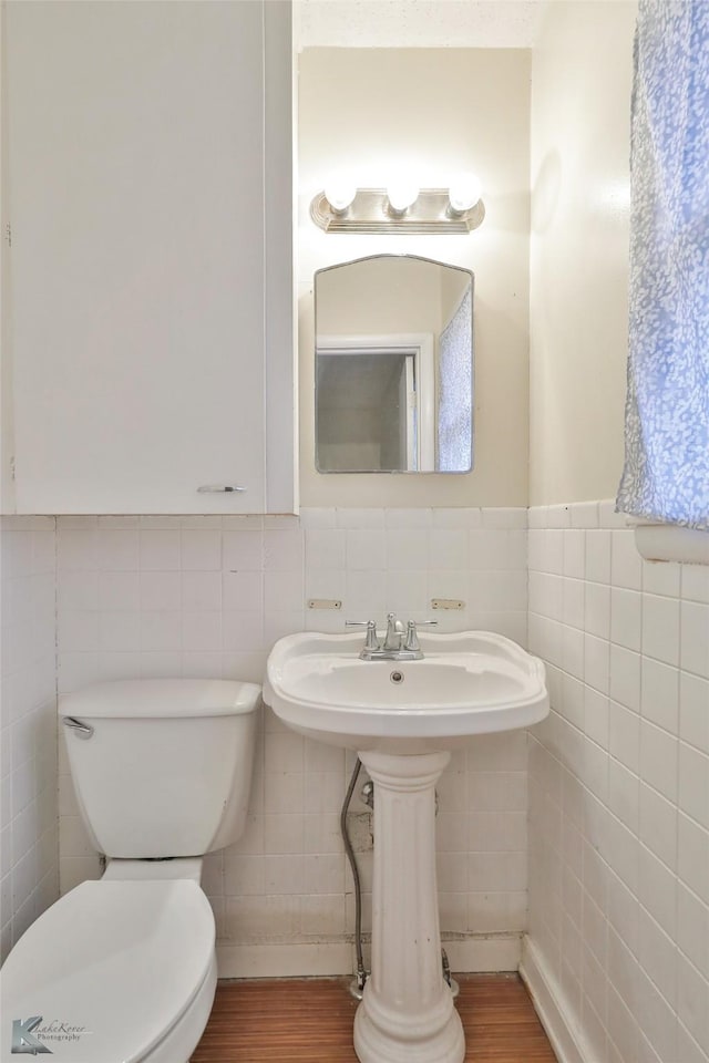 bathroom with toilet, wood-type flooring, and tile walls