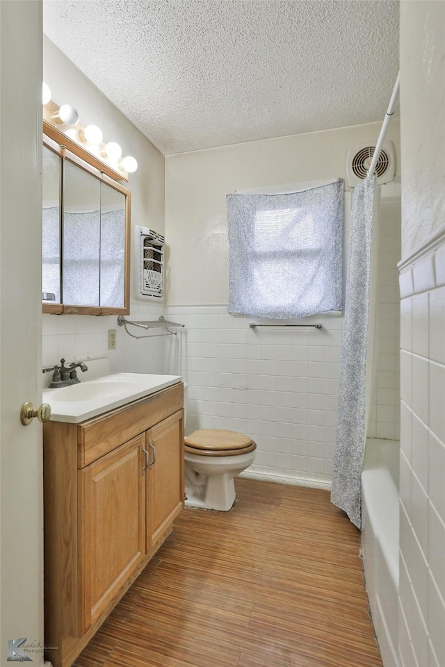 full bathroom with vanity, wood-type flooring, shower / bathtub combination with curtain, tile walls, and toilet