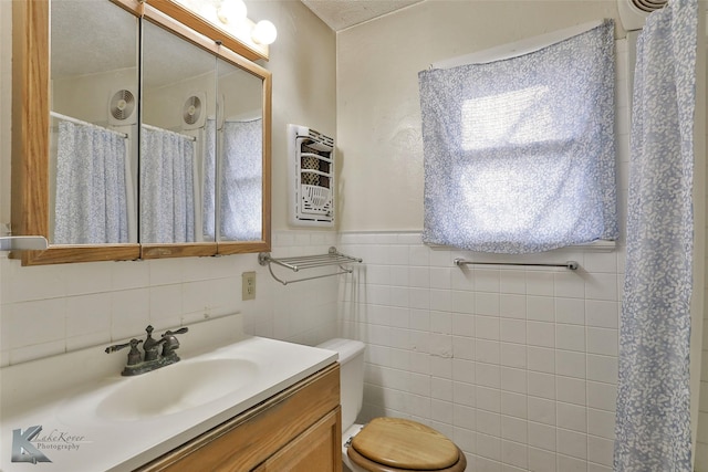 bathroom with a textured ceiling, vanity, tile walls, and heating unit