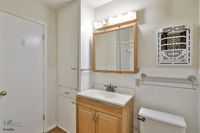 bathroom with vanity, toilet, and tile walls