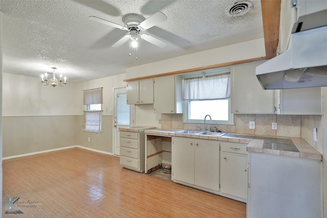 kitchen featuring tasteful backsplash, white cabinetry, tile counters, and sink