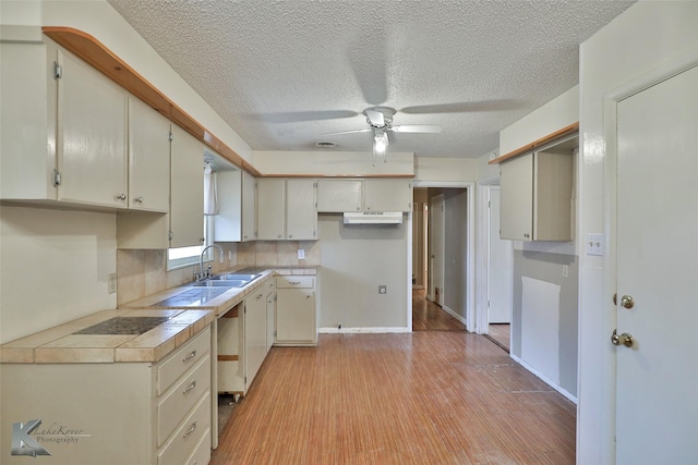 kitchen featuring sink, ceiling fan, tasteful backsplash, tile counters, and light hardwood / wood-style floors