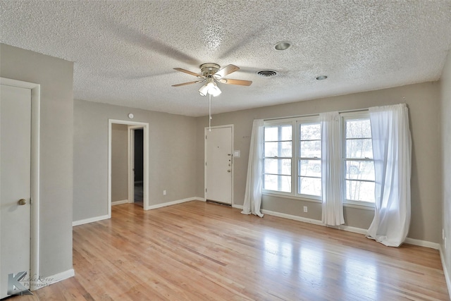 spare room featuring ceiling fan, light hardwood / wood-style flooring, and a textured ceiling