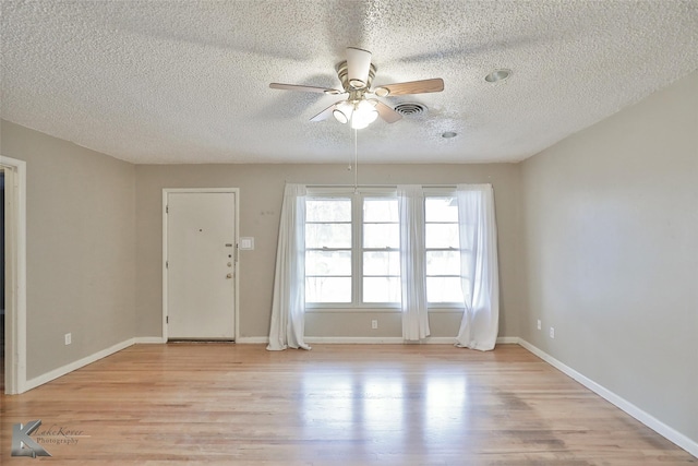 spare room with ceiling fan, a textured ceiling, and light wood-type flooring