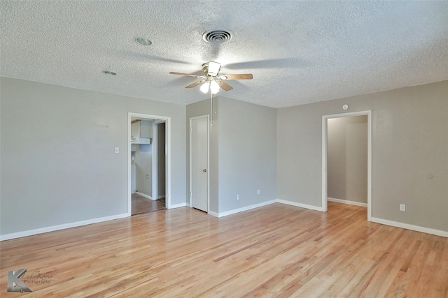 spare room with ceiling fan, a textured ceiling, and light wood-type flooring