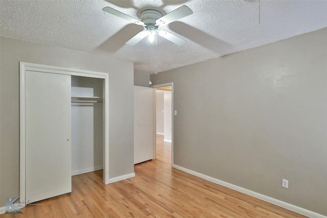 unfurnished bedroom with a closet, a textured ceiling, light hardwood / wood-style floors, and ceiling fan