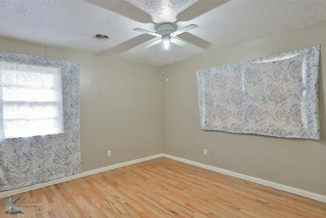 spare room featuring ceiling fan, wood-type flooring, and a textured ceiling