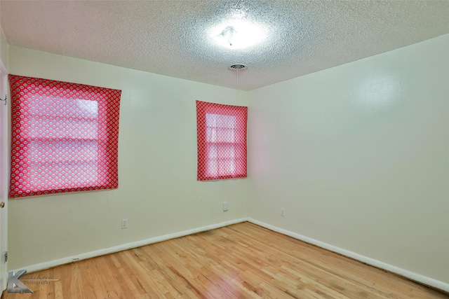 unfurnished room with a textured ceiling and hardwood / wood-style flooring