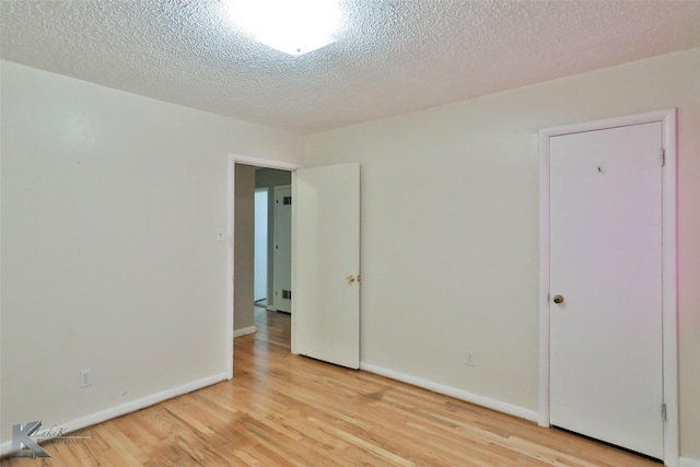 spare room featuring light hardwood / wood-style flooring and a textured ceiling