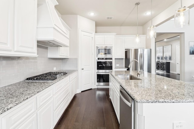 kitchen with custom exhaust hood, stainless steel appliances, sink, pendant lighting, and white cabinets