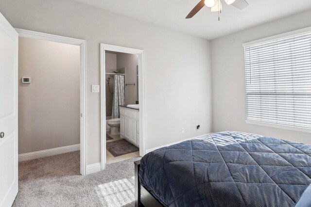 carpeted bedroom with ensuite bath and ceiling fan