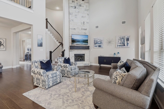 living room featuring dark wood-type flooring, a fireplace, and a high ceiling