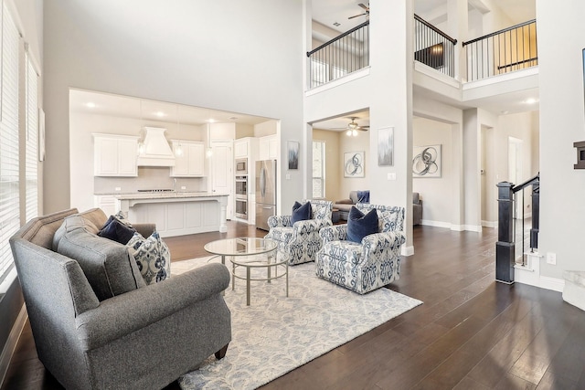 living room with ceiling fan, dark hardwood / wood-style floors, and a high ceiling