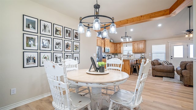 dining area with beam ceiling, ceiling fan with notable chandelier, and light hardwood / wood-style flooring