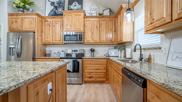 kitchen featuring pendant lighting, stainless steel appliances, light stone countertops, and sink