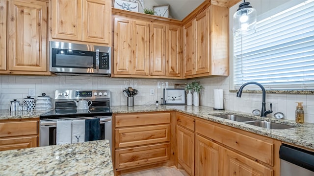 kitchen featuring light stone countertops, appliances with stainless steel finishes, sink, and decorative backsplash