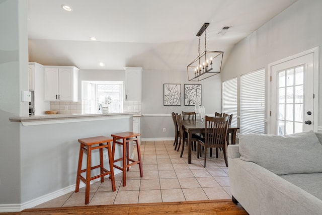 dining area featuring light tile patterned flooring, vaulted ceiling, and an inviting chandelier