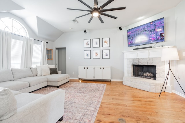 living room with ceiling fan, light wood-type flooring, a fireplace, and lofted ceiling