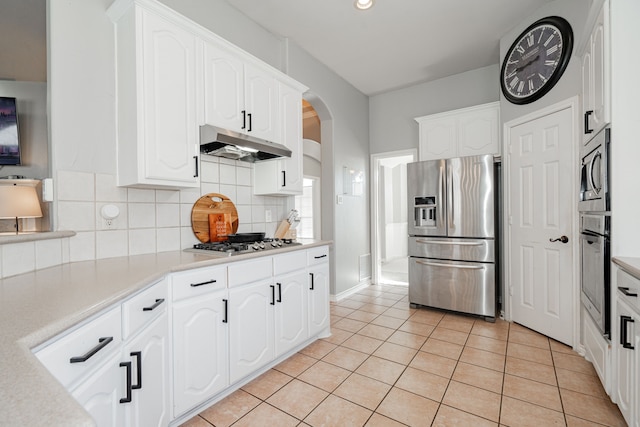 kitchen with decorative backsplash, white cabinetry, light tile patterned floors, and stainless steel appliances