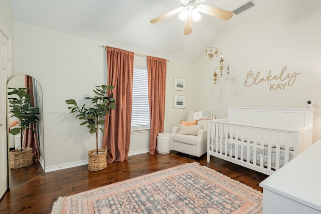 bedroom with dark hardwood / wood-style floors, vaulted ceiling, a nursery area, and ceiling fan