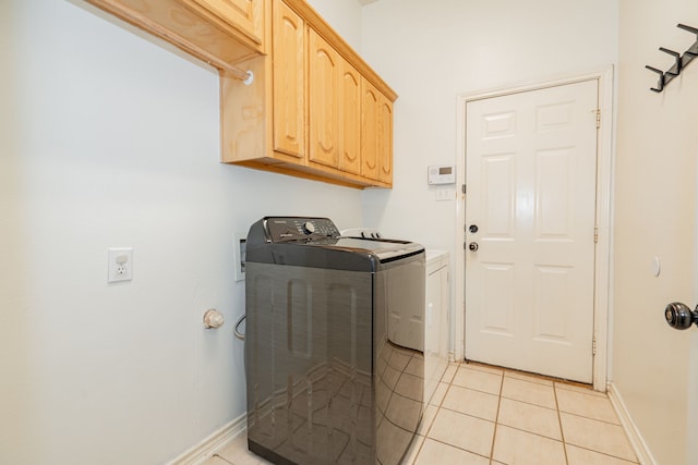 clothes washing area featuring cabinets, washer and clothes dryer, and light tile patterned flooring