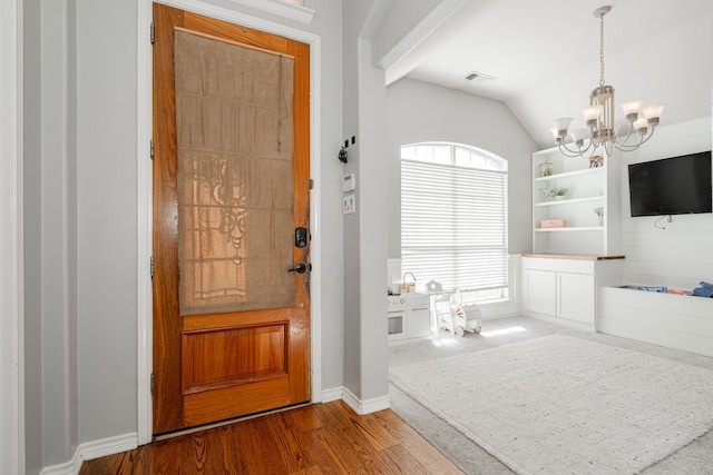 entryway with hardwood / wood-style floors, a chandelier, and lofted ceiling