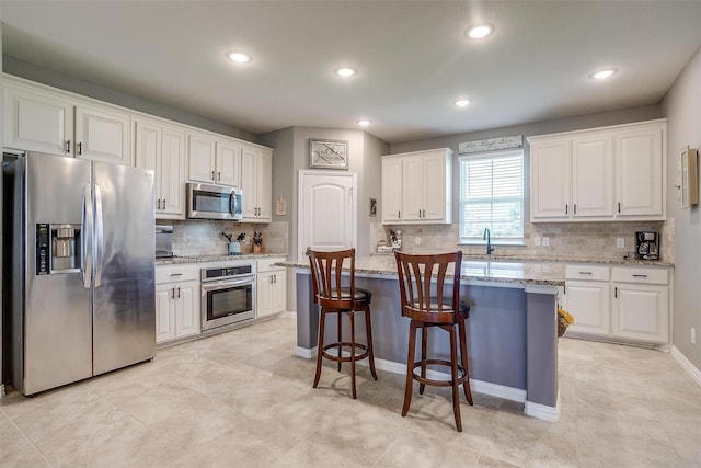 kitchen with appliances with stainless steel finishes, a center island, white cabinetry, and sink