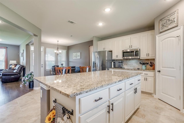 kitchen with appliances with stainless steel finishes, a center island, white cabinetry, and pendant lighting