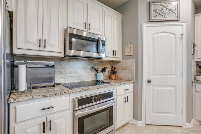 kitchen featuring white cabinetry, stainless steel appliances, light stone counters, decorative backsplash, and light tile patterned floors