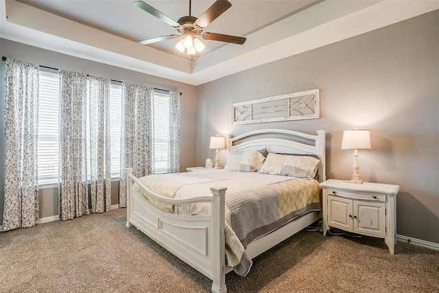 bedroom with ceiling fan, a raised ceiling, light carpet, and multiple windows